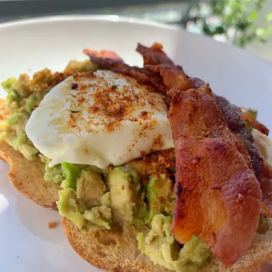 Avocado toast with poached egg, bacon, and dukkah spices.