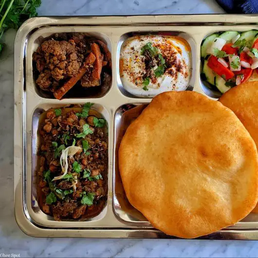 Tangy, savory, and spicy, Amritsari chole with bhatura, raita, salad, and achar