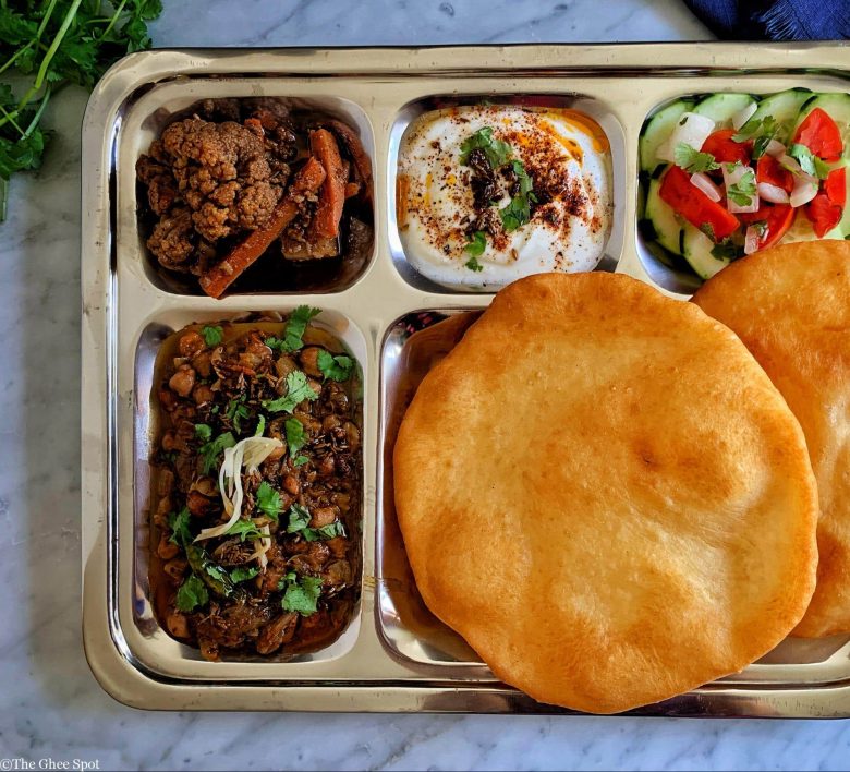 Tangy, savory, and spicy, Amritsari chole with bhatura, raita, salad, and achar