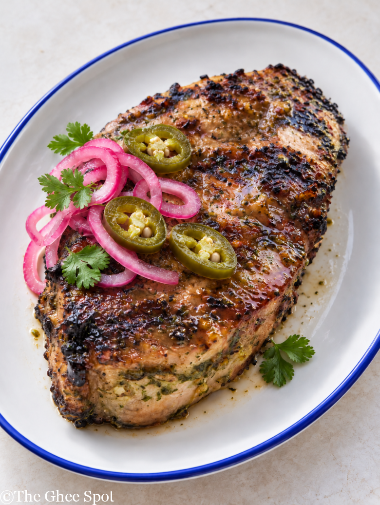 jalepeno pork chop garnished with pickled shallots and jalepenos.